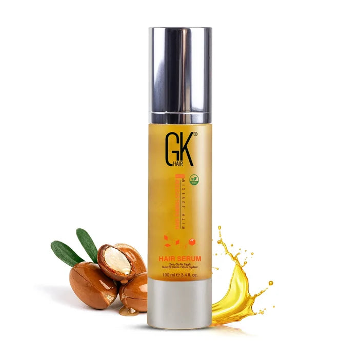 GK Hair Argan Oil Serum 100 ml gold bottle labeled Hair Serum, silver pump cap, argan nuts and an oil splash beside it