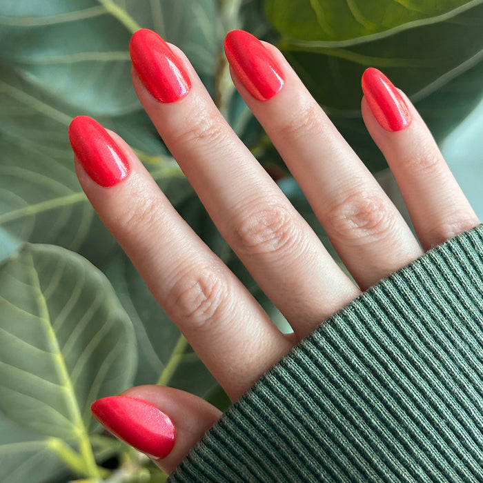Hand with medium oval bright pinky-red shimmer nails using Rodeo Queen - Press-On | Medium | Oval for an easy mani