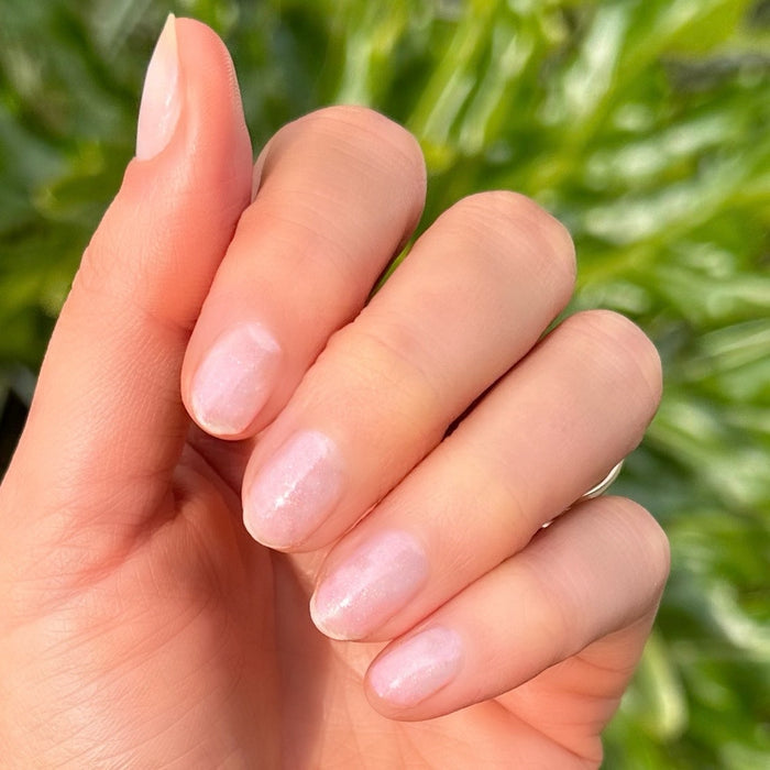 Hand with natural nails softly shimmering in sunlight using Starshower rose gold polish for an elegant at home mani