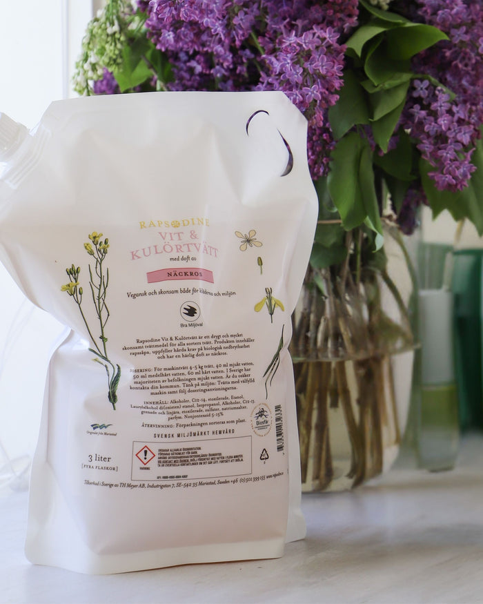 Rapsodines refill för vit- och kulörtvätt med doft av näckros i naturlig tvättmiljö med lila blommor