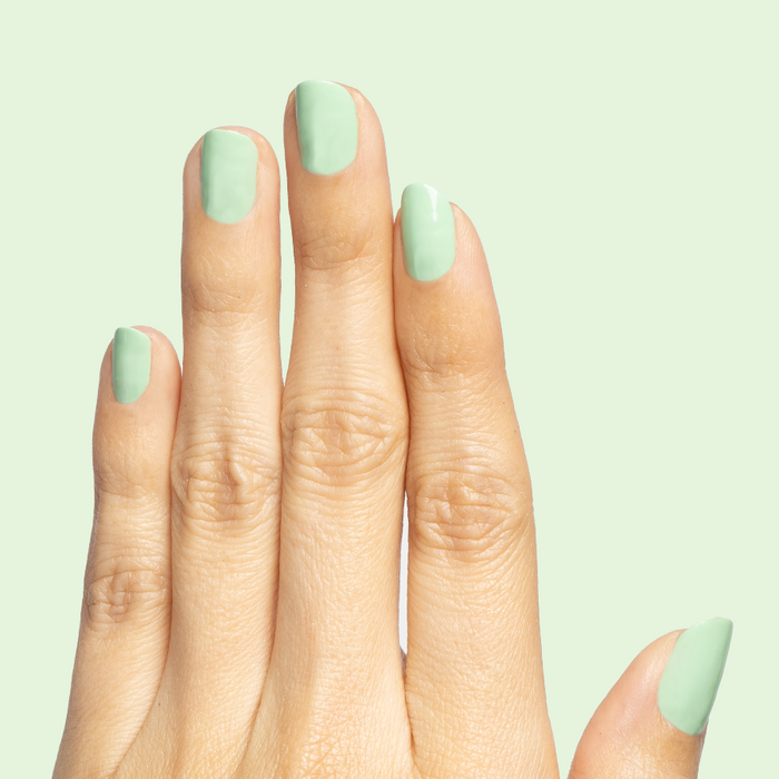 Hand with nails painted in pastel green Aced It for a fresh and long-lasting at home manicure look
