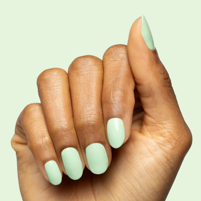 Hand with nails painted in pastel green Aced It for a smooth and fresh at-home manicure look