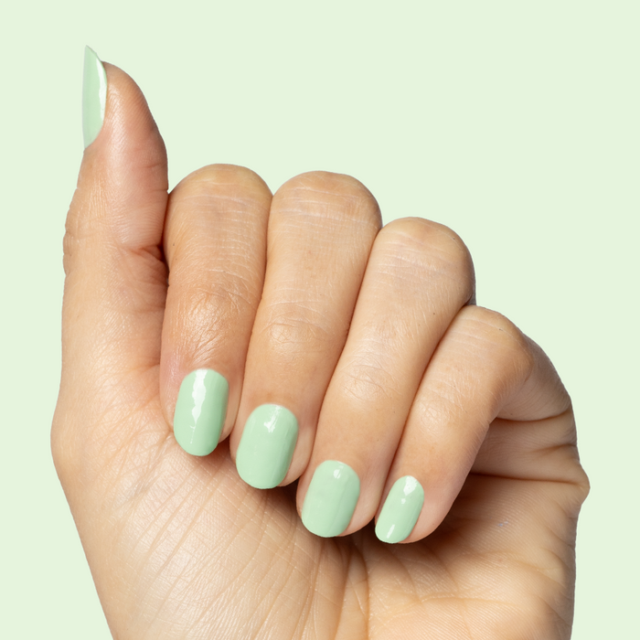 Hand displaying nails painted with Aced It pastel green polish for a fresh and smooth at-home mani look
