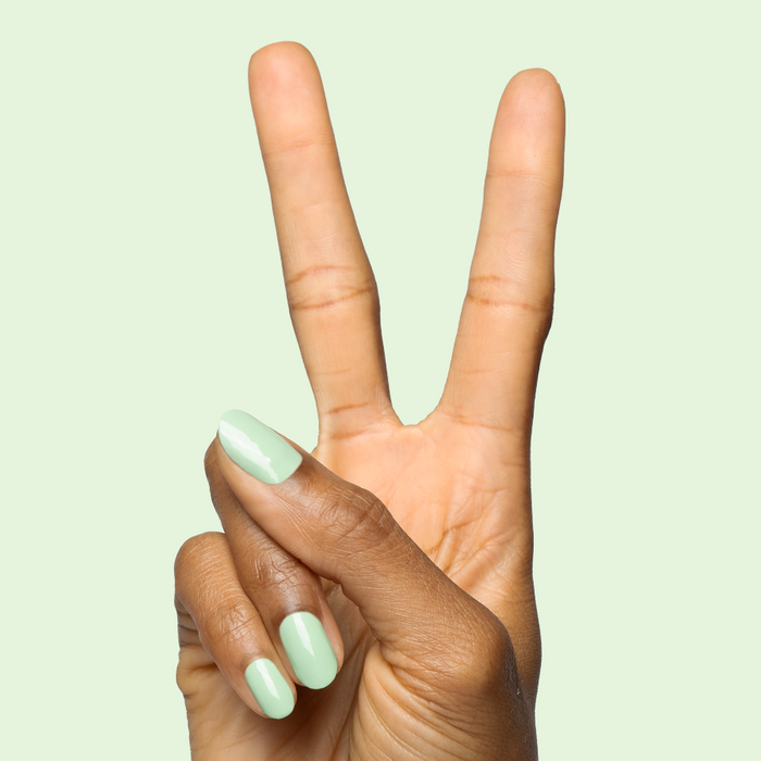 Hand showing peace sign with nails coated in Aced It pastel green for a fresh quick-dry mani look