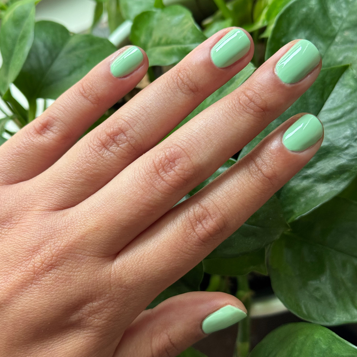 Hand with nails painted in glossy pastel green Aced It polish for a smooth quick dry at-home manicure look