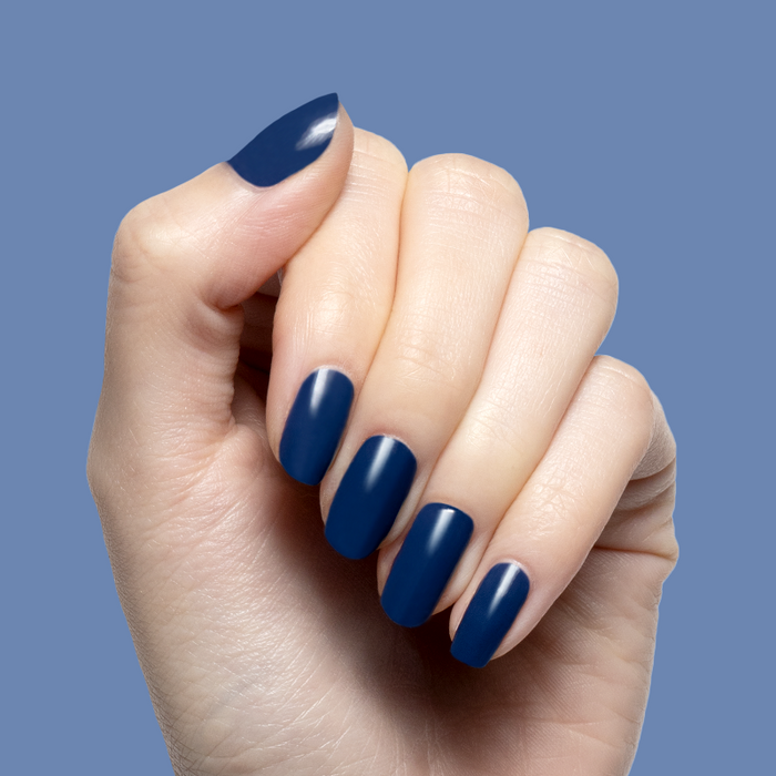 Hand with smooth navy blue gel polish on nails featuring Ack, A Shark! for a long-lasting manicure look