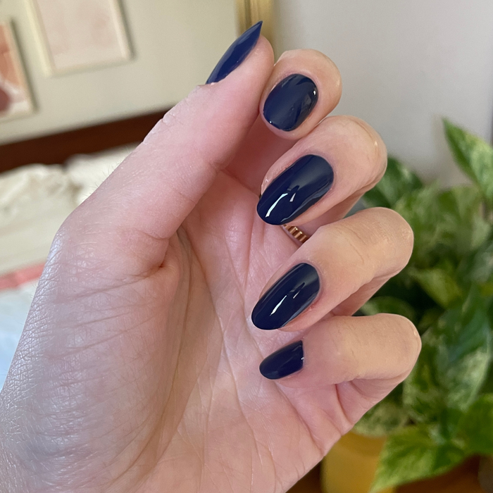 Hand with glossy navy blue gel polish nails painted with Ack, A Shark! for a smooth, long-lasting mani look