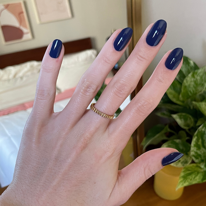 Hand with glossy gel polish nails painted in deep navy blue using Ack, A Shark! for a smooth, long-lasting manicure