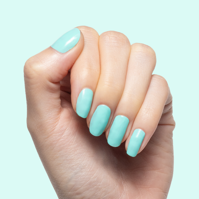 Hand with smooth nails painted in All Manis on Deck bright blue-green gel polish showing fresh at home manicure