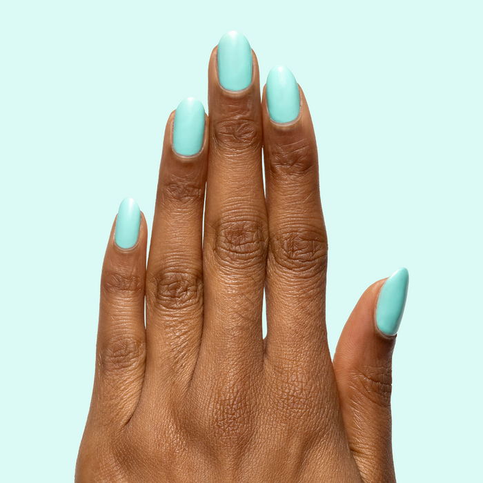 Hand with nails painted in All Manis on Deck bright blue-green gel polish showing fresh, glossy manicure at home