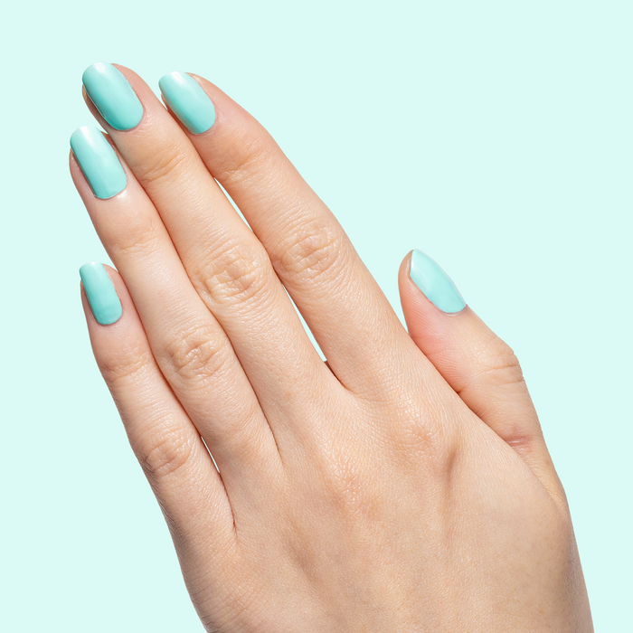 Hand with nails painted in glossy All Manis on Deck bright blue-green gel polish showing smooth manicure at home