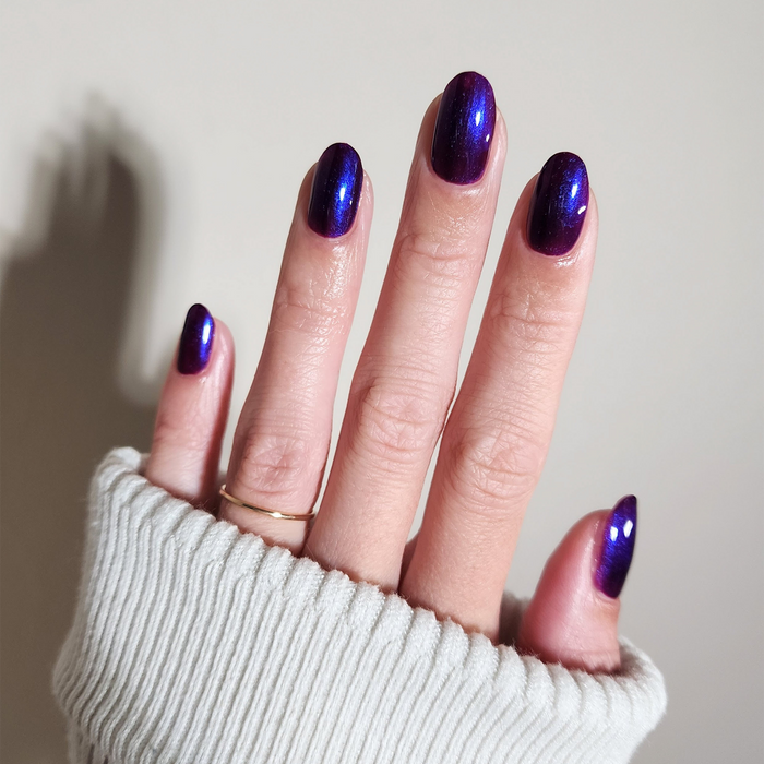 Amethyst Kiss iridescent purple nail polish manicure on a light skin tone with a white sweater
