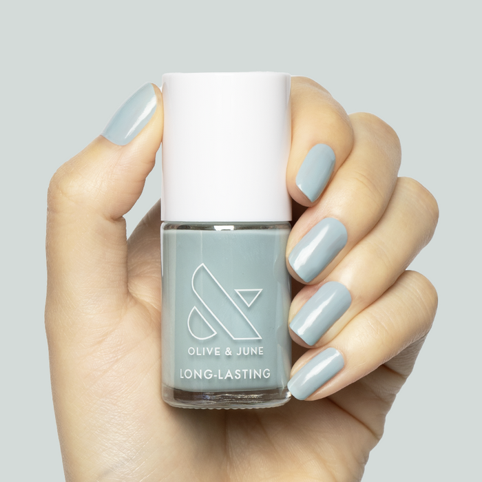 Hand holding Bandana Blue nail polish with nails painted a pastel true blue gel finish for a long-lasting mani