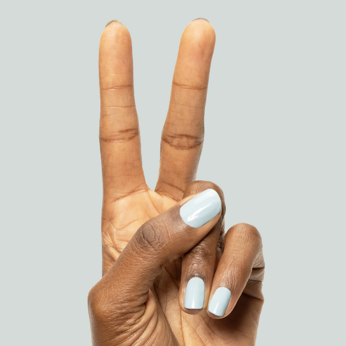 Hand showing peace sign with nails painted glossy Bandana Blue gel polish for a stylish manicure look