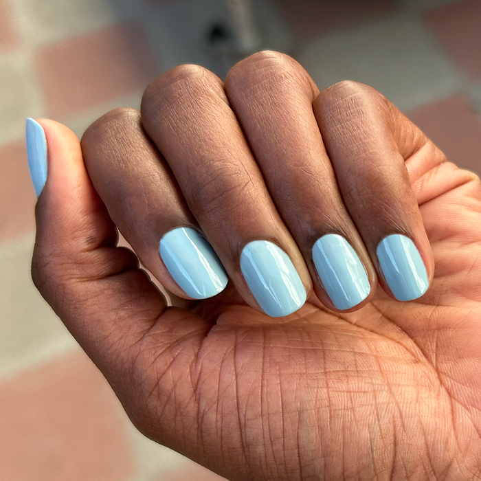 Hand with medium-length nails painted in glossy Bandana Blue gel polish for a fresh, long-lasting manicure look