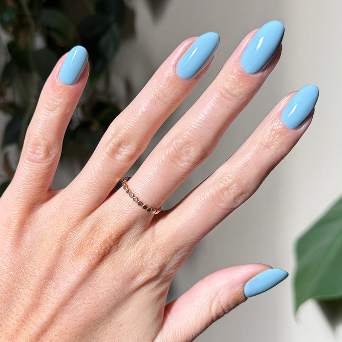 Hand with elongated nails painted in glossy pastel Bandana Blue gel polish for a smooth and lasting manicure look