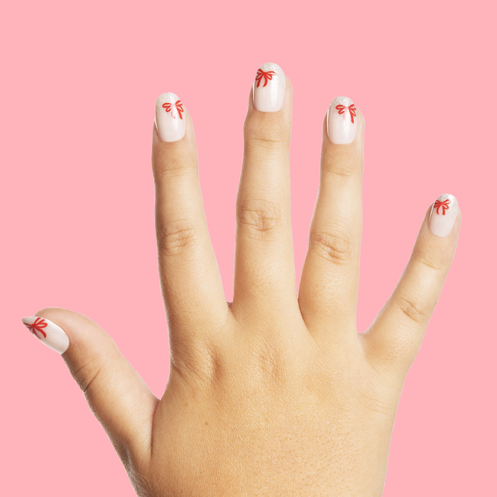 Big Bow Energy - Pressies | Short Medium | Round showing pale press-on nails with red bow accents on hand against pink background