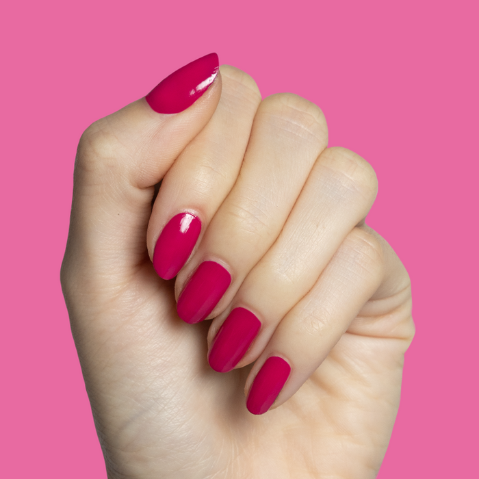 Hand with nails painted in Biggest Bow magenta pink gel polish for a vibrant at-home mani by Olive and June