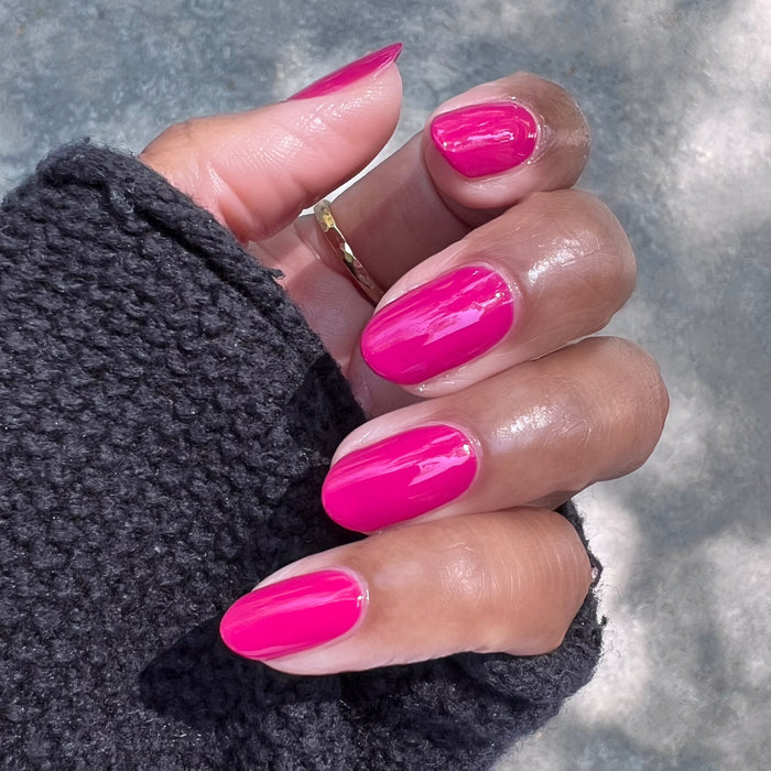 Hand with glossy nails painted in Biggest Bow vibrant magenta pink gel polish showing fresh at-home manicure