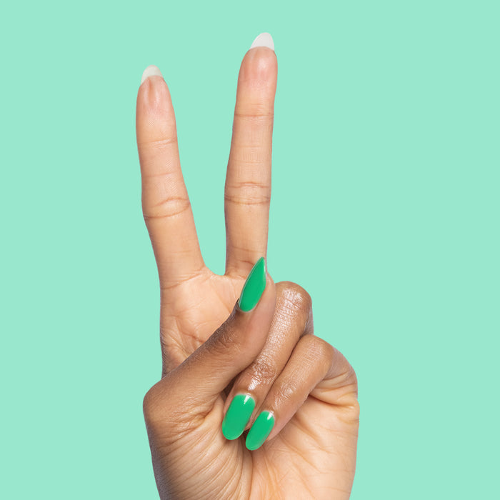 Hand showing two fingers painted with Bocce Ball green nail polish on a solid mint background