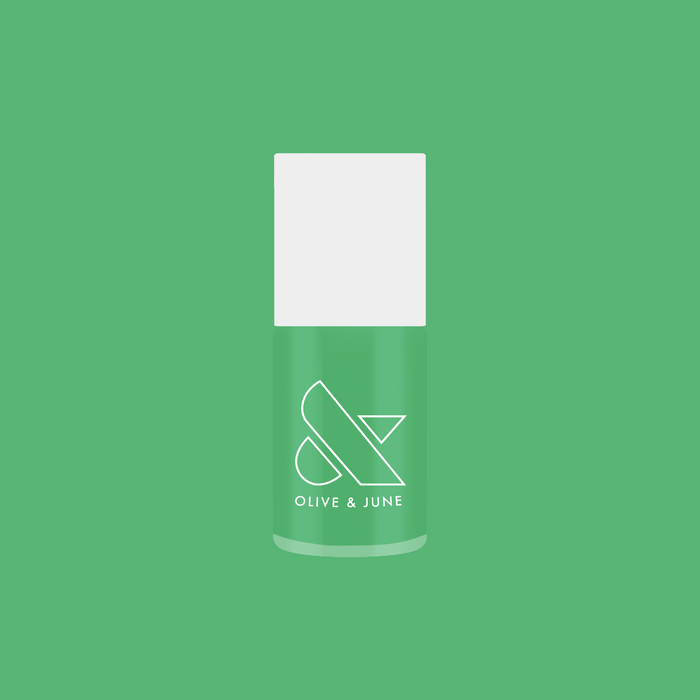 Olive & June bottle of Bocce Ball green nail polish on solid green background for fresh mani look