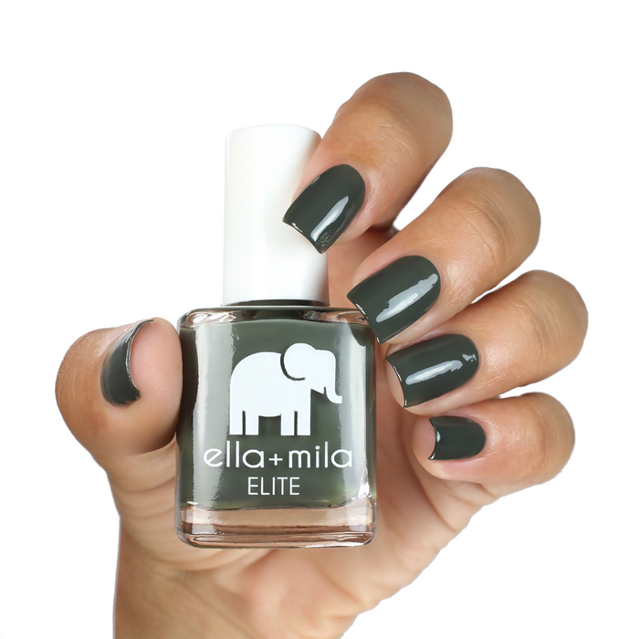 Bon Voyage olive green nail polish on a medium skin tone, hand holding the bottle