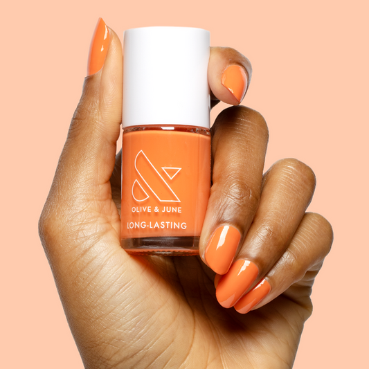 Hand with glossy nails painted vibrant tangerine using Bounce Back long-lasting polish by Olive and June