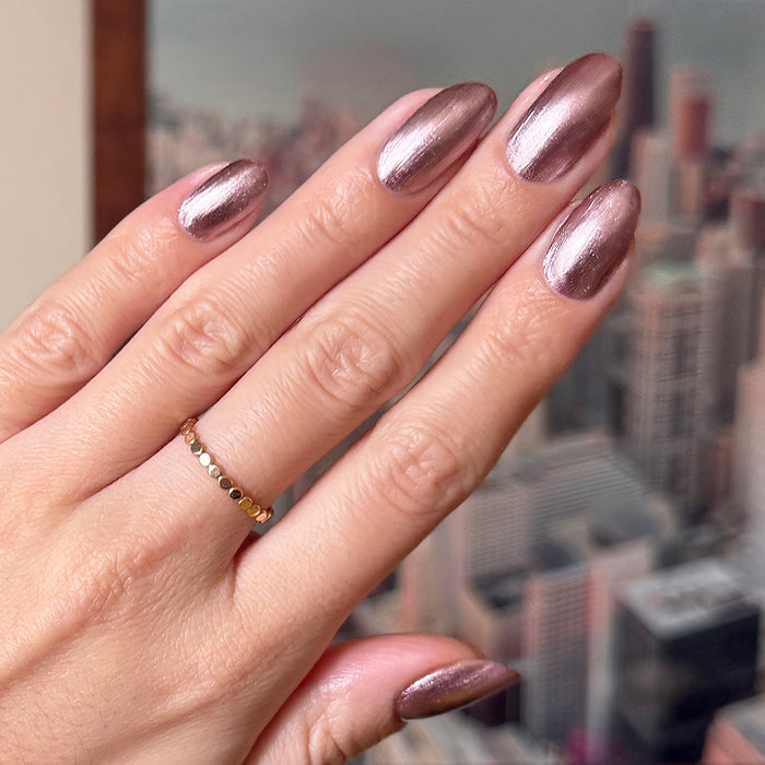 Hand showing metallic neutral pink nails polished with Bronze Velvet for a shiny at-home manicure look