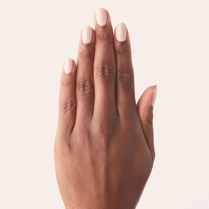 Hand with nails painted in creamy peach Cable Knit gel polish against soft neutral background for at home mani