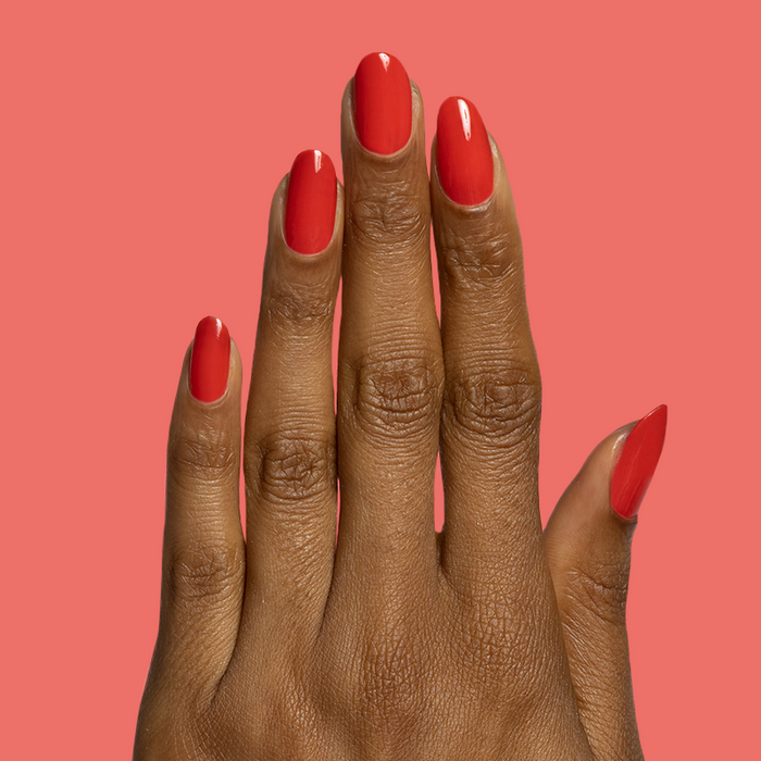 Hand with nails painted in bright red Candy Dipped gel polish for a glossy at-home mani by Olive and June
