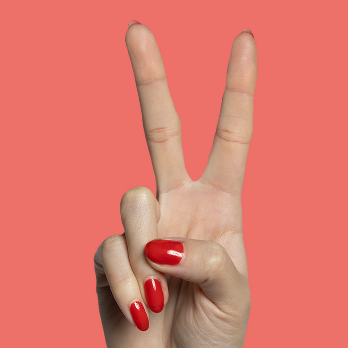 Hand showing two fingers with nails painted in glossy Candy Dipped red gel polish for at-home manicure