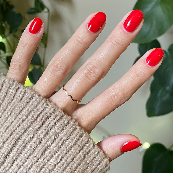 Hand with nails painted in glossy Candy Dipped red jelly polish showing a fresh at-home manicure by Olive and June