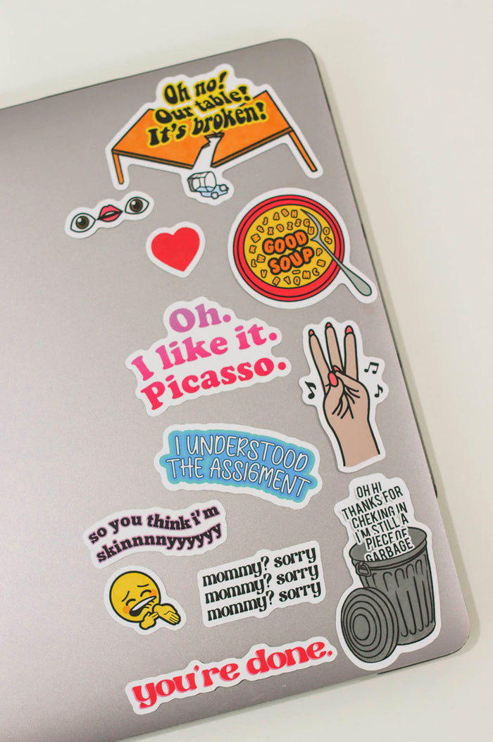 stickers on a laptop- oh no our table is broken, eye lips eye, heart emoji, alphabet soup that says "good soup", "oh. I like it. Picasso.", 3 Finger Taps to musica, "I understood the assignment", "so you think I'm skinnnnyyyy", ice on my veins emoji, "mommy sorry" x 3 times, "oh hi thanks for checkin in. I'm still a piece of garbage" in a trash can, "you're done"