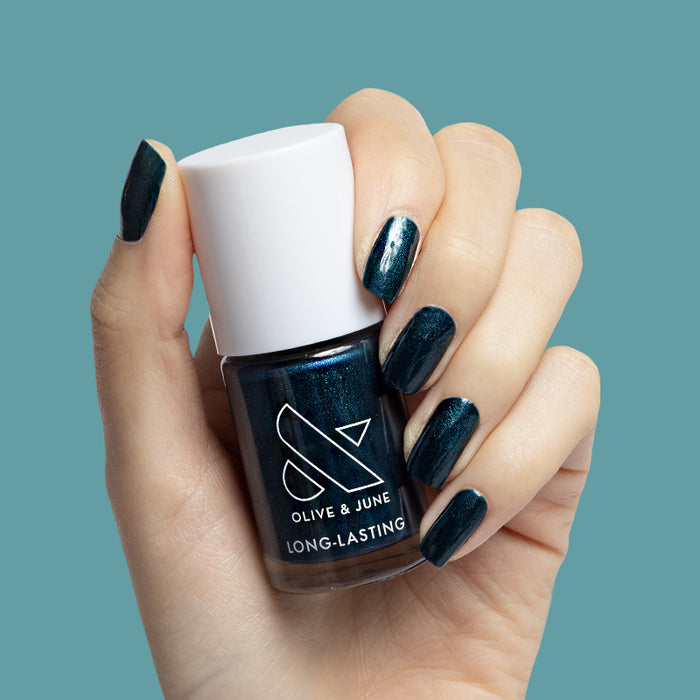 Hand holding Olive and June Dancing Green long-lasting nail polish with deep emerald green mani on short nails