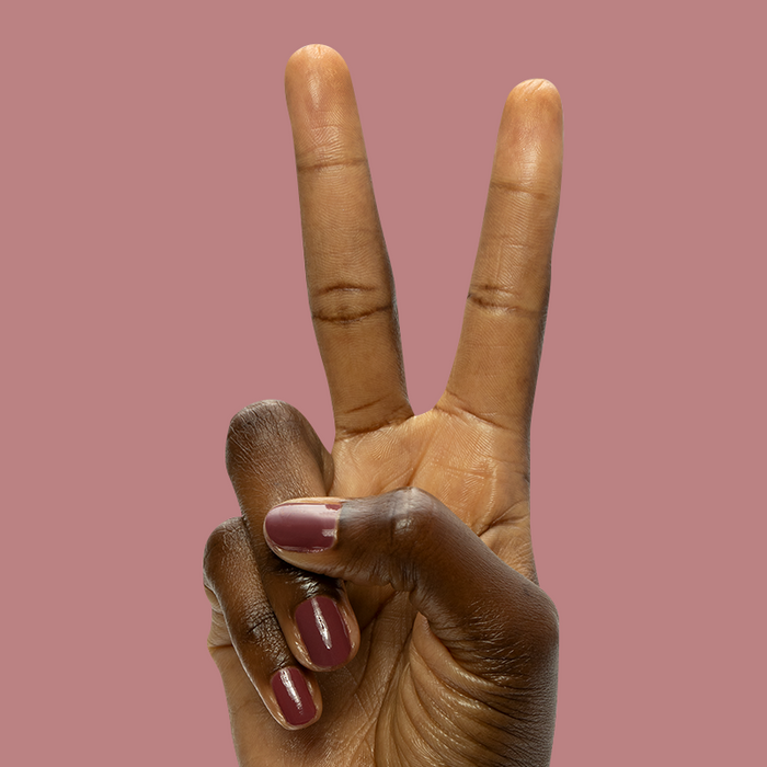 Hand showing peace sign with short nails polished in Don’t Spill on the White Couch deep dusty berry red gel polish manicure