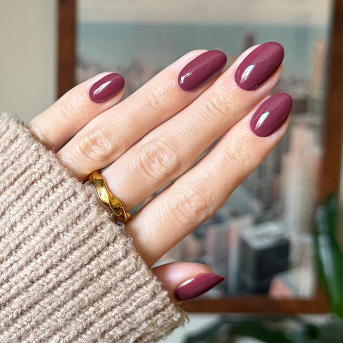 Hand with almond-shaped nails in Don’t Spill on the White Couch deep dusty berry red gel polish manicure