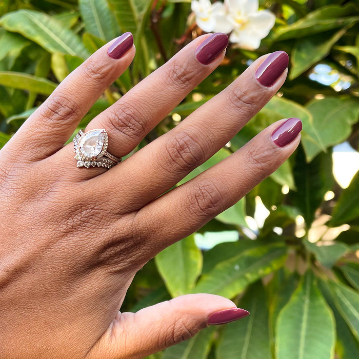 Hand with medium-length nails polished in Don’t Spill on the White Couch deep dusty berry red gel polish outdoors