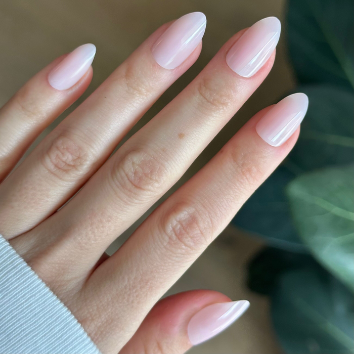 Hand with light skin tone wearing Dream Job - Press-On | Medium | Almond nails in milky sheer pink for a natural mani look