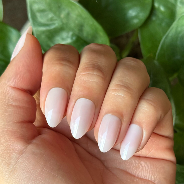 Hand with natural skin tone wearing Dream Job - Press-On | Medium | Almond nails in sheer milky pink for a polished mani look