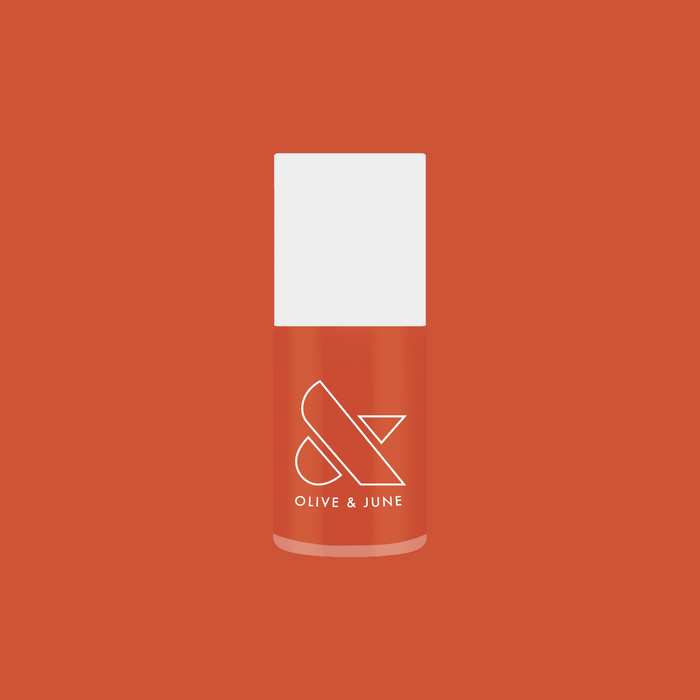 Bottle of Flowerpot burnt orange nail polish by Olive and June on matching terracotta background