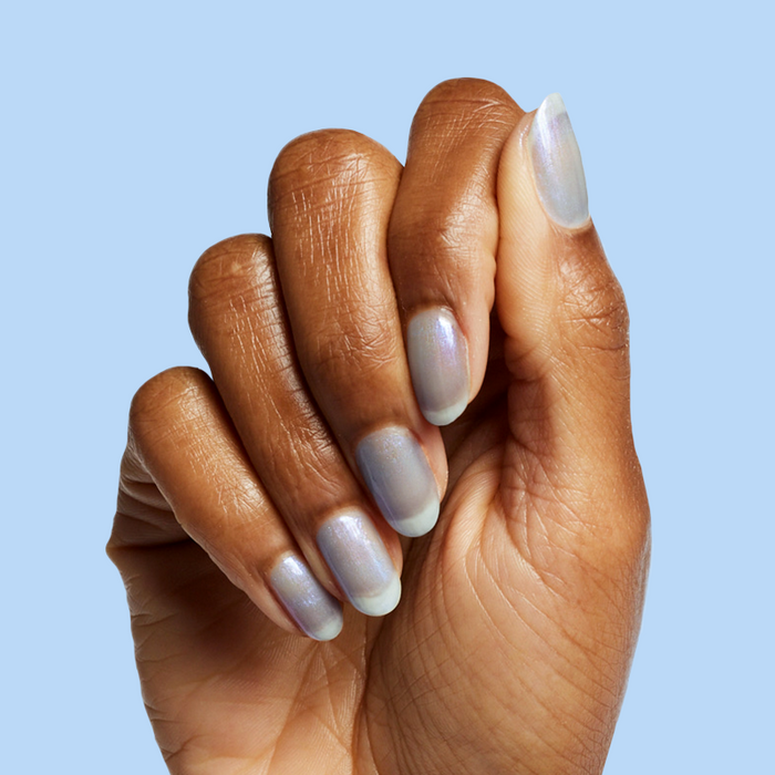 Hand with nails painted in cool lavender-blue iridescent manicure using Friend or Anemone? gel polish on blue background