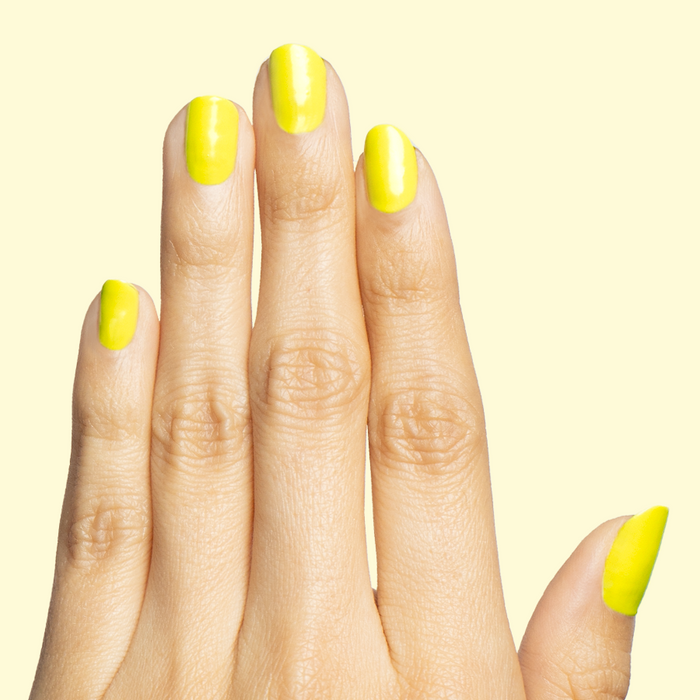 Hand displaying nails painted in bright electric yellow Game Set Mani polish for a vibrant at-home manicure look