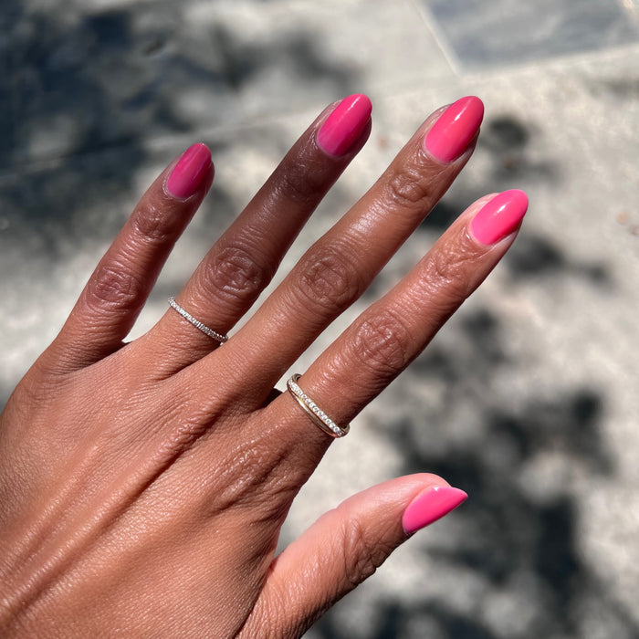 Hand with oval-shaped nails painted in vibrant neon pink Guava Gloss long-lasting quick dry polish outdoors