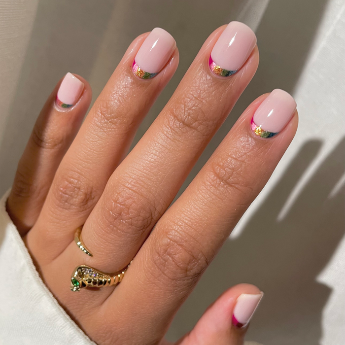 Heart of Gold gold glitter French tip nail art on a light skin tone with a gold ring