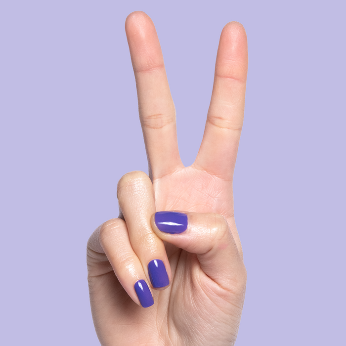 Hand showing glossy nails painted with House of O&J polish in deep purple against a lavender background