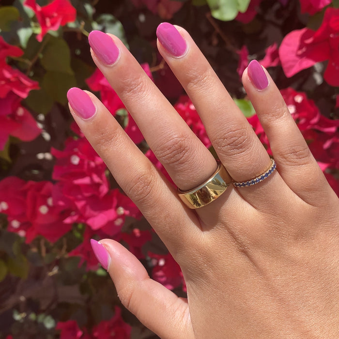 Hand with nails painted in bright floral hot magenta using How Do You Spell Bougainvillea? polish outdoors