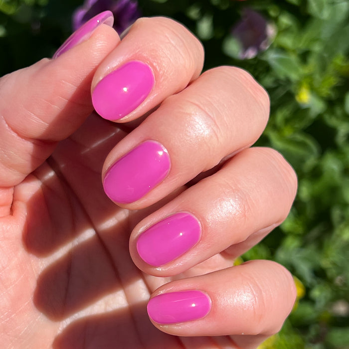 Hand with nails painted in bright floral hot magenta using How Do You Spell Bougainvillea? gel polish outdoors