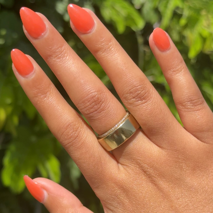 Hand with almond-shaped nails painted in bright orange gel polish I’ll Take Another Spritz for a smooth mani look