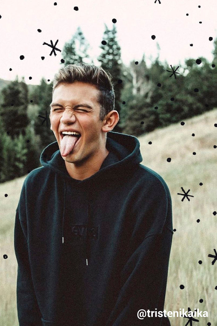 boy sticking his tongue out to camera with black drawn sparkles and spots on the photo