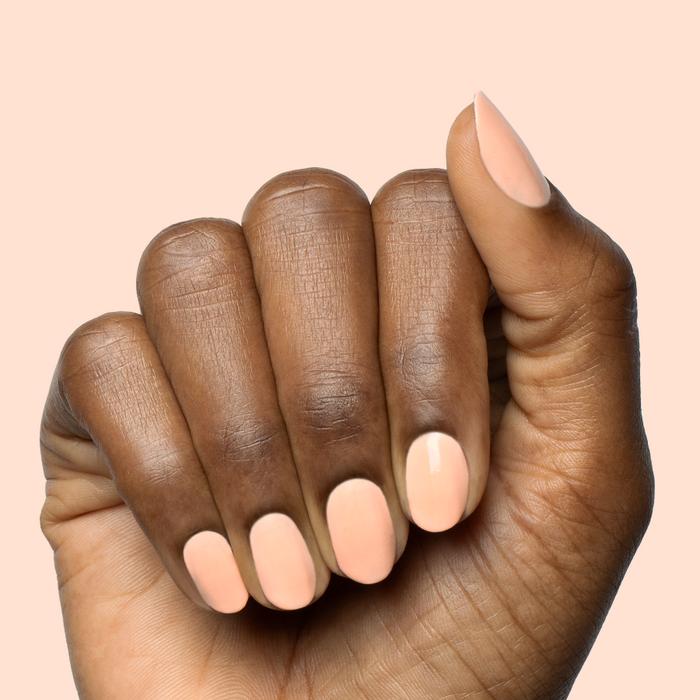 Hand with smooth nails painted in pastel melon shade It’s Serving Melon Cocktails polish for a fresh at-home manicure